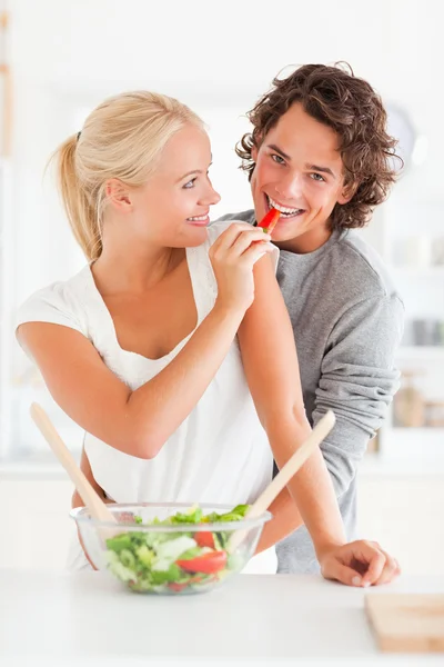 Portrait of a woman giving a slice of pepper to her fiance — Stock Photo, Image