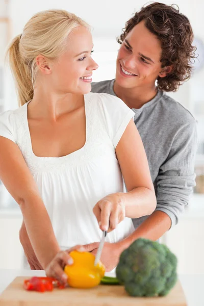 Retrato de um casal sorridente cortando pimenta — Fotografia de Stock