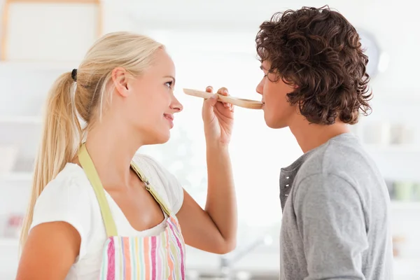 Blonde woman making her fiance tasting her meal — Stock Photo, Image