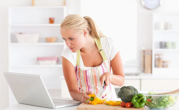 使用一台笔记本电脑来做饭的女人 — 图库照片