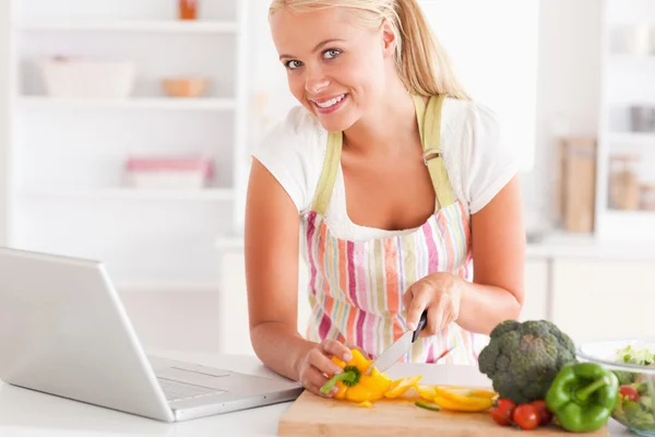 Close up of a blonde woman using a laptop to cook — Stock Photo, Image