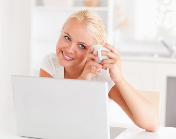 Mulher tomando um café ao usar seu laptop — Fotografia de Stock