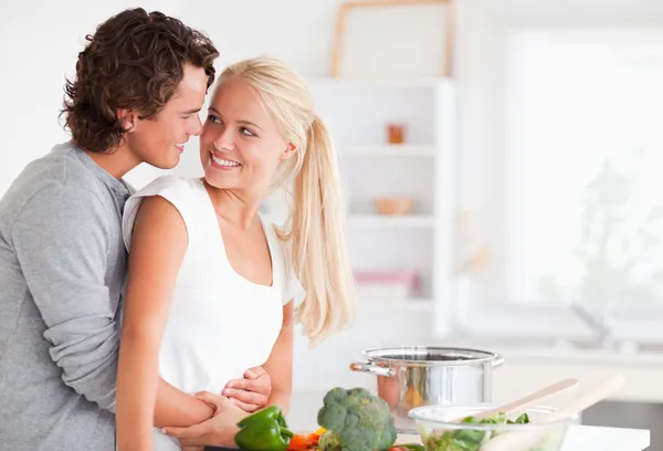 No amor casal abraçando enquanto cozinha — Fotografia de Stock