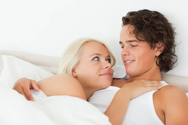 Close up de um casal deitado em uma cama abraçando — Fotografia de Stock