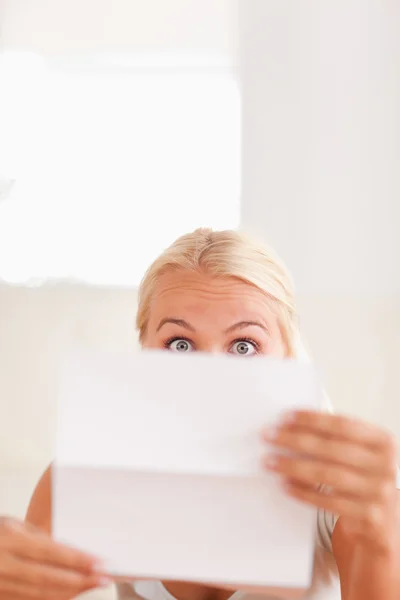 Mulher loira chocada lendo uma carta — Fotografia de Stock