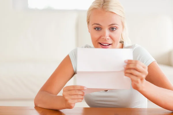 Woman looking at a letter in amazement — Stock Photo, Image