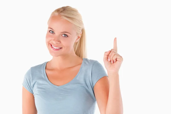 Blond kvinna som pekar på copyspace tittar in i kameran — Stock fotografie