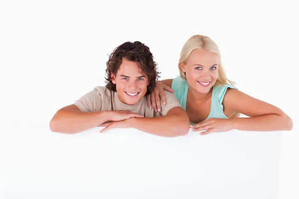 Bonito casal inclinado em um quadro branco — Fotografia de Stock