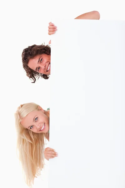 Paar verstopt achter een whiteboard — Stockfoto