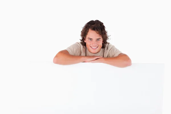 Gülümseyen adam beyaz tahta üzerine eğilerek — Stok fotoğraf