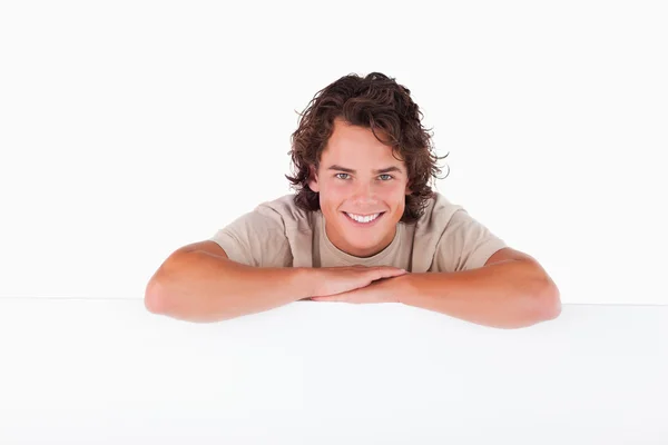 Sonriente hombre apoyado en una pizarra blanca mirando a la cámara — Foto de Stock