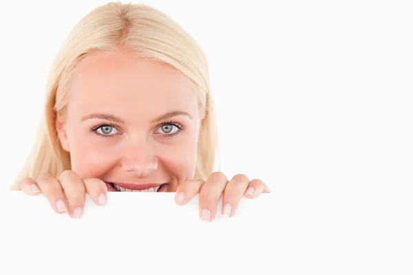 Sorrindo mulher espreitando sobre um quadro branco — Fotografia de Stock