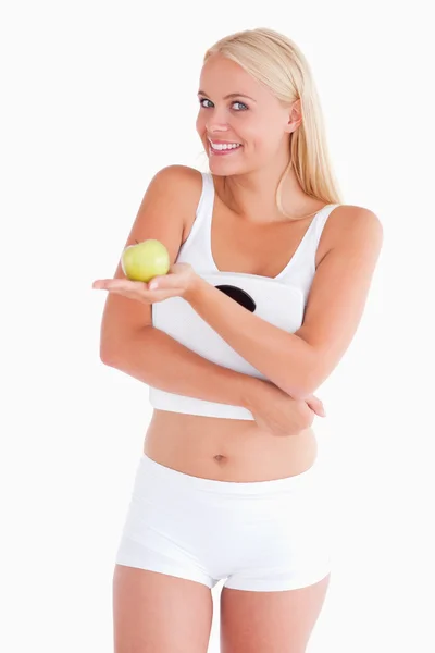 Young woman holding an apple and a scale — Stock Photo, Image