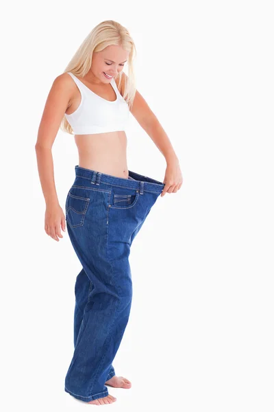 Smiling woman wearing to big jeans — Stock Photo, Image