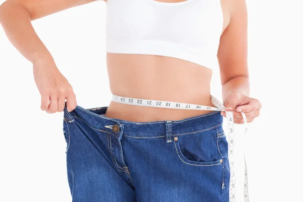 Mulher medindo sua cintura enquanto vestindo jeans muito grandes — Fotografia de Stock
