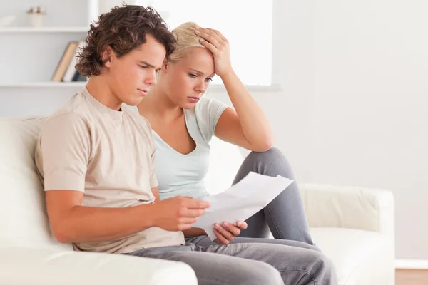 Unhappy couple holding an invoice — Stock Photo, Image
