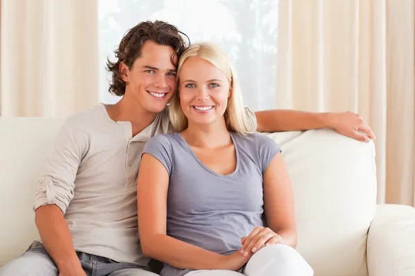 Sorrindo casal sentado em um sofá — Fotografia de Stock