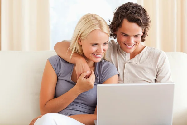 Sonriendo joven pareja usando un ordenador portátil — Foto de Stock