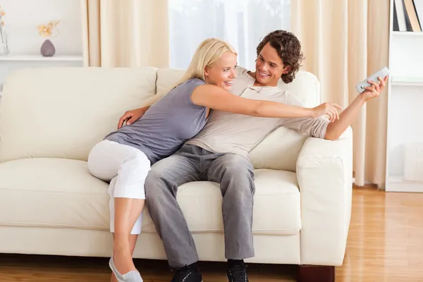 Smiling couple fighting for the remote — Stock Photo, Image