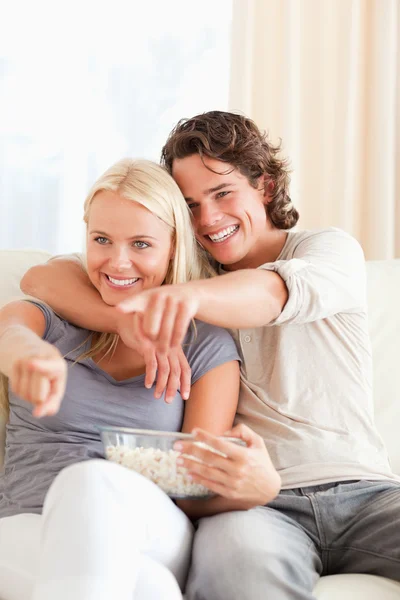 Retrato de um casal assistindo TV enquanto come pipocas — Fotografia de Stock