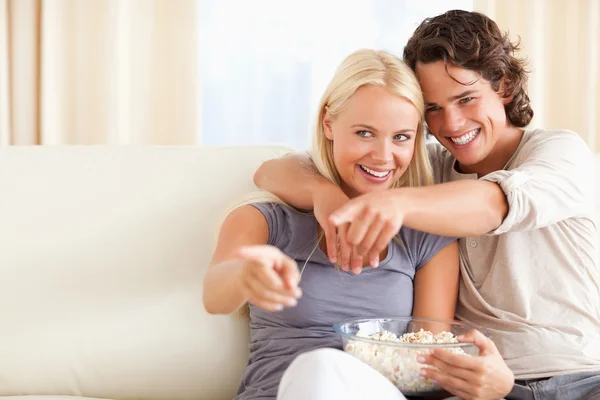 Linda pareja viendo televisión mientras come palomitas de maíz — Foto de Stock