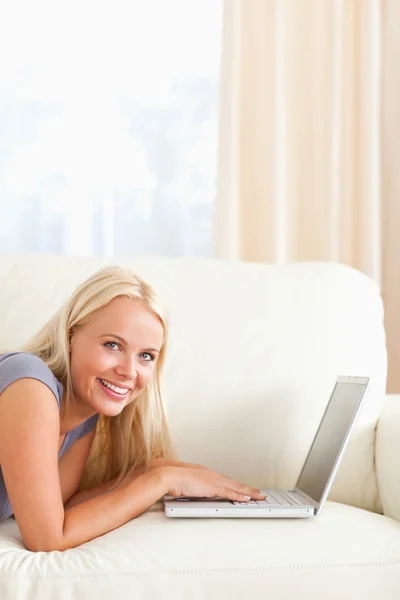 Donna sdraiata su un divano con un computer portatile — Foto Stock