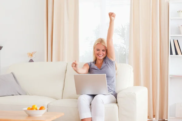 Mulher levantando os braços enquanto usa um laptop — Fotografia de Stock