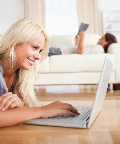 Porträt einer Frau, die einen Laptop benutzt, während ihr Mann liest — Stockfoto