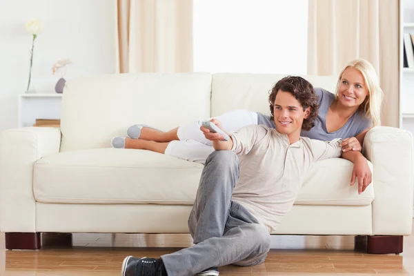 Смеющаяся милая пара смотрит телевизор — стоковое фото