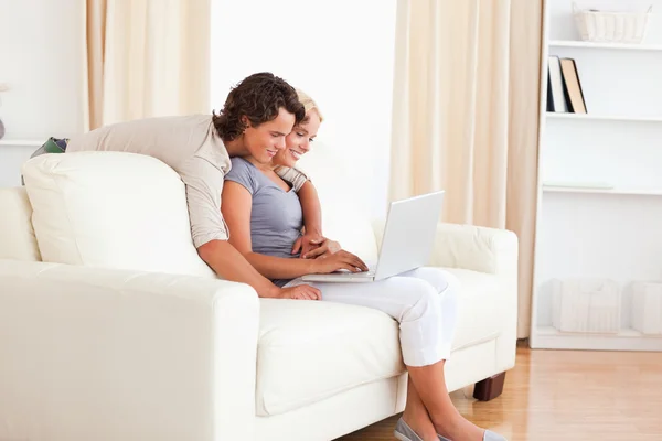 Gülümseyen genç bir çift bir dizüstü bilgisayar kullanarak — Stok fotoğraf