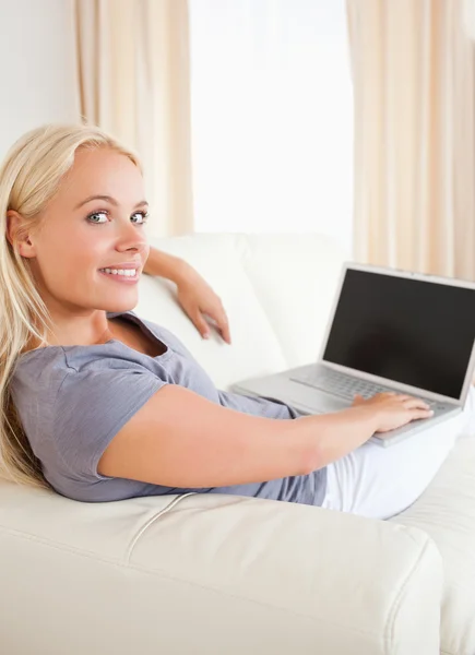 Porträtt av en blond kvinna växlar på sin laptop — Stockfoto
