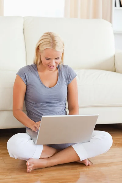 女人坐在地上的同时使用一台笔记本电脑 — 图库照片