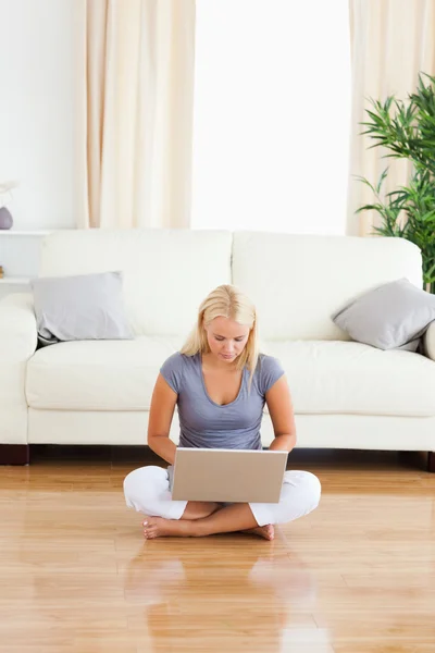 Portrait of a woman using a laptop while sitting on the floor — Stock Photo, Image