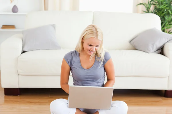 Happy woman using a notebook while sitting on the floor — Stock Photo, Image