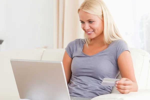 Frau schaut auf ihren Laptop, während sie ihre Kreditkarte hält — Stockfoto