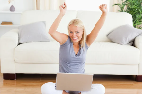 Glad kvinna använder en bärbar dator medan du sitter på golvet — Stockfoto