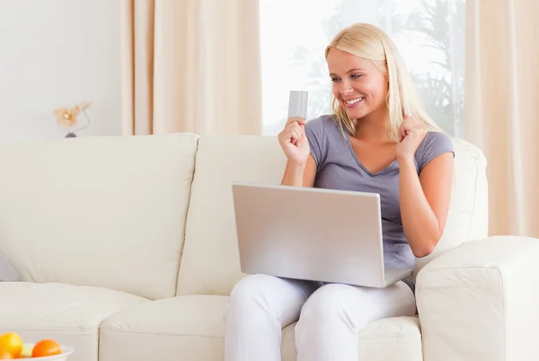 Beautiful blonde woman cheering while shopping online — Stock Photo, Image