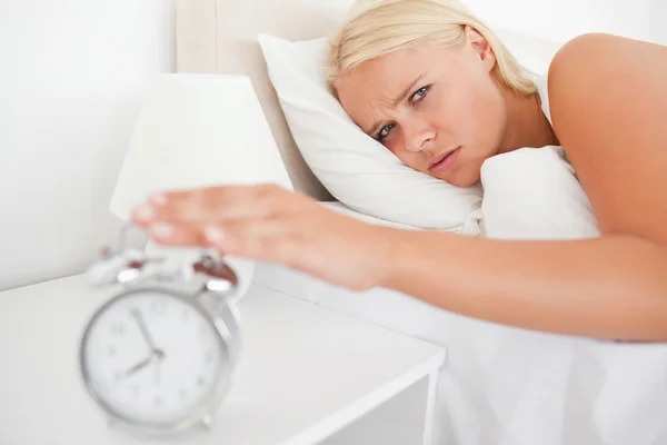 疲れている女性を目覚め、目覚し時計によって — Stock fotografie
