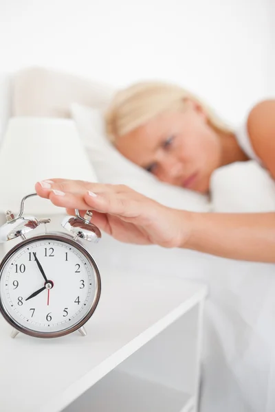Retrato de uma mulher infeliz desligando seu despertador — Fotografia de Stock