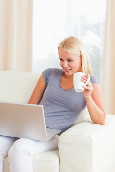 Portrait of a woman having a tea while using a laptop — Stock Photo, Image