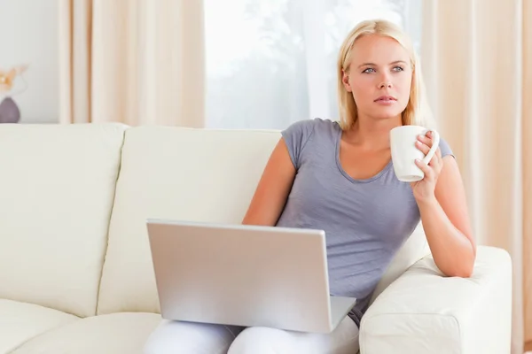 Kvinna med en te medan du håller en laptop — Stockfoto