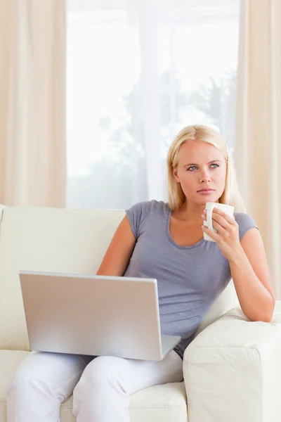 Retrato de mulher tomando um chá enquanto segura um laptop — Fotografia de Stock