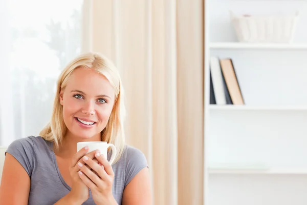 Kvinna sitter på en soffa med en kopp te — Stockfoto