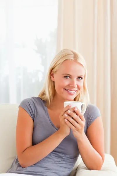 Retrato de uma mulher sentada em um sofá com uma xícara de chá — Fotografia de Stock