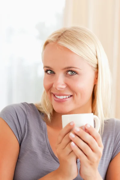 Porträt einer Frau, die mit einer Tasse Kaffee auf einer Couch sitzt — Stockfoto
