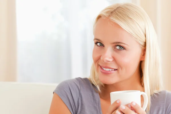 Close up of a woman sitting on a couch with a cup of coffee — Stock Photo, Image