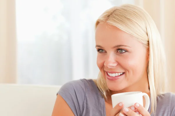 Close up of a woman sitting on a couch with a cup of tea — Stock Photo, Image