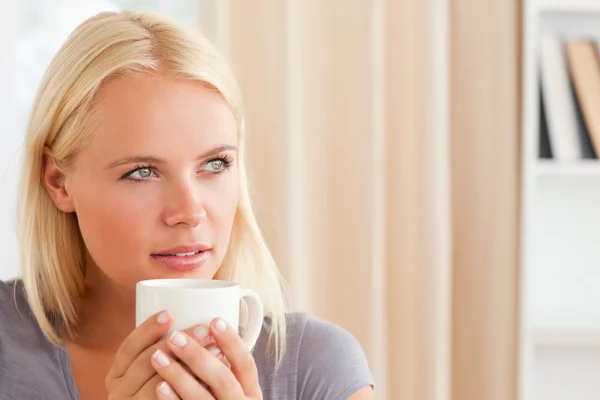 Close up of a woman sitting on a sofa with a cup of tea — Stock Photo, Image