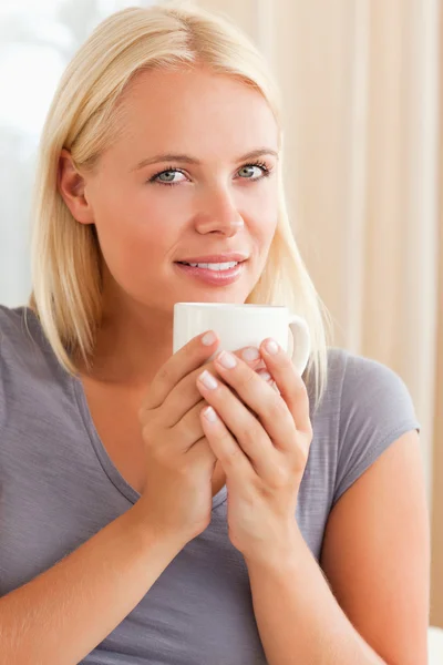 Portret spokojna kobieta siedzi na kanapie z filiżanką herbaty — Zdjęcie stockowe