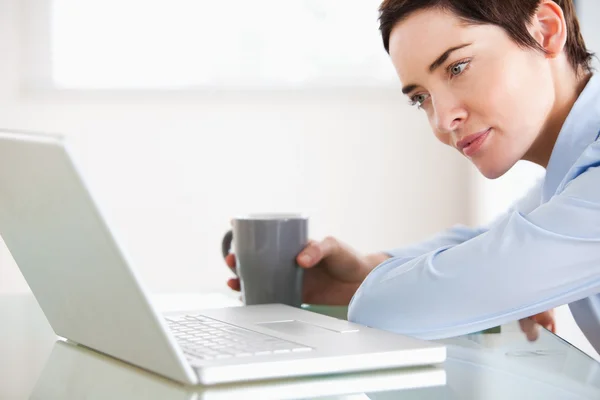 Brunette woman with a laptop and a cup — Stock Photo, Image